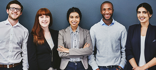 Group of people standing against a wall smiling at the camera