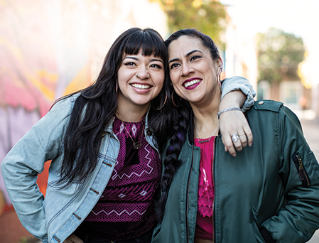 Two young caucasian women leaning into each other and smiling