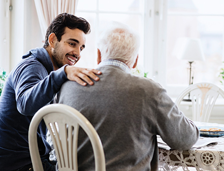 young man sitting with senior man in conversation