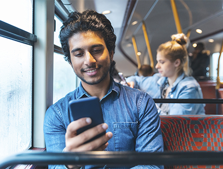 Man using his phone on a bus.
