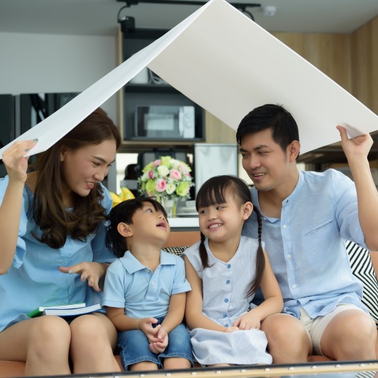 Family of four holding paper roof over their heads