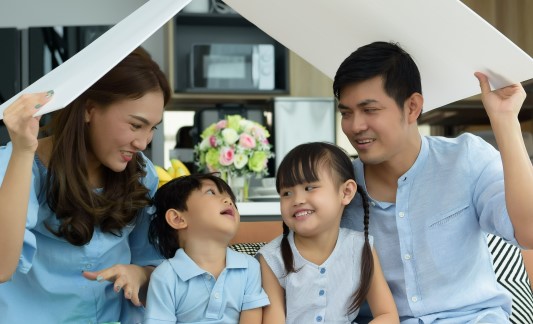 Happy Asian family underneath a homemade roof