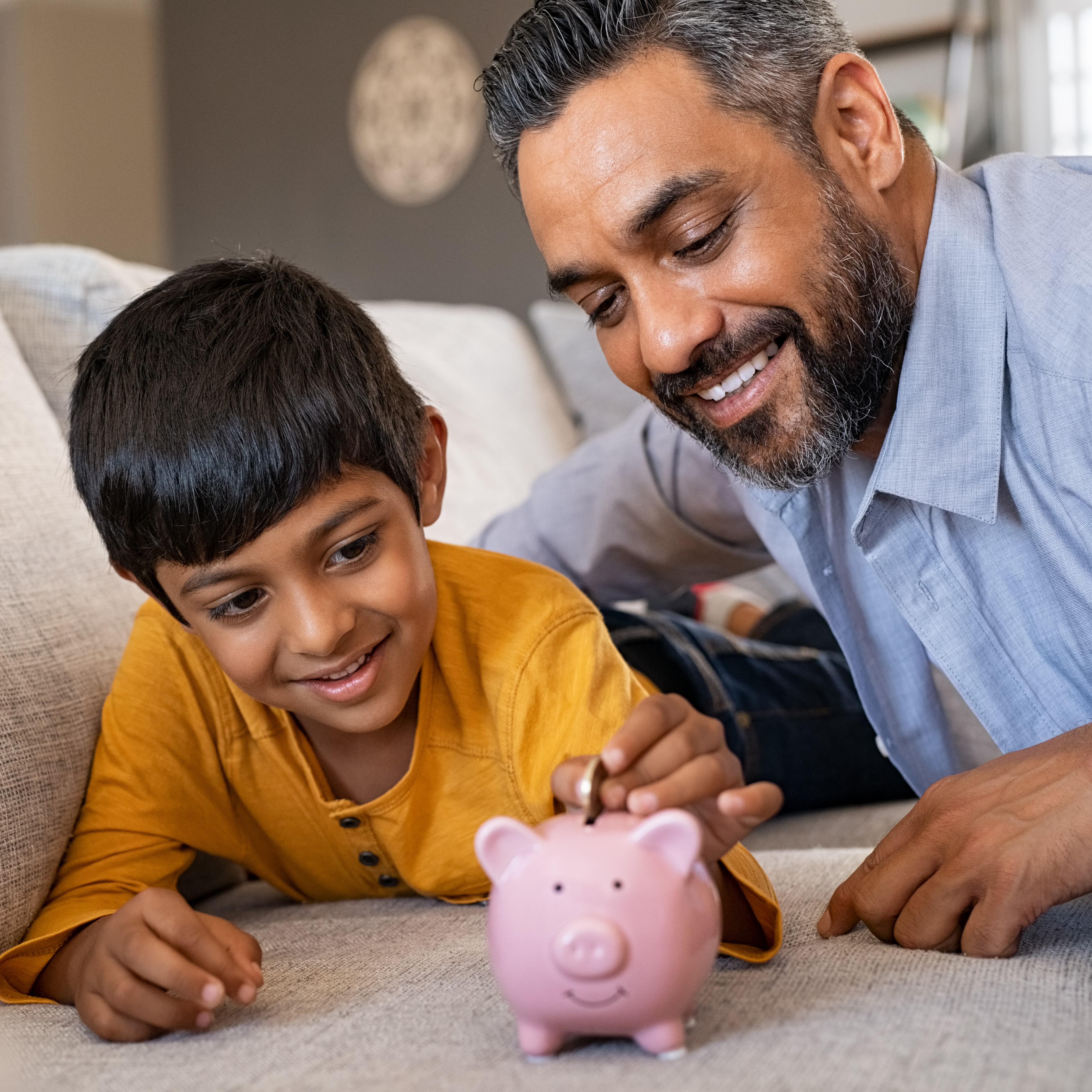 Father and son putting coins into a piggy bank